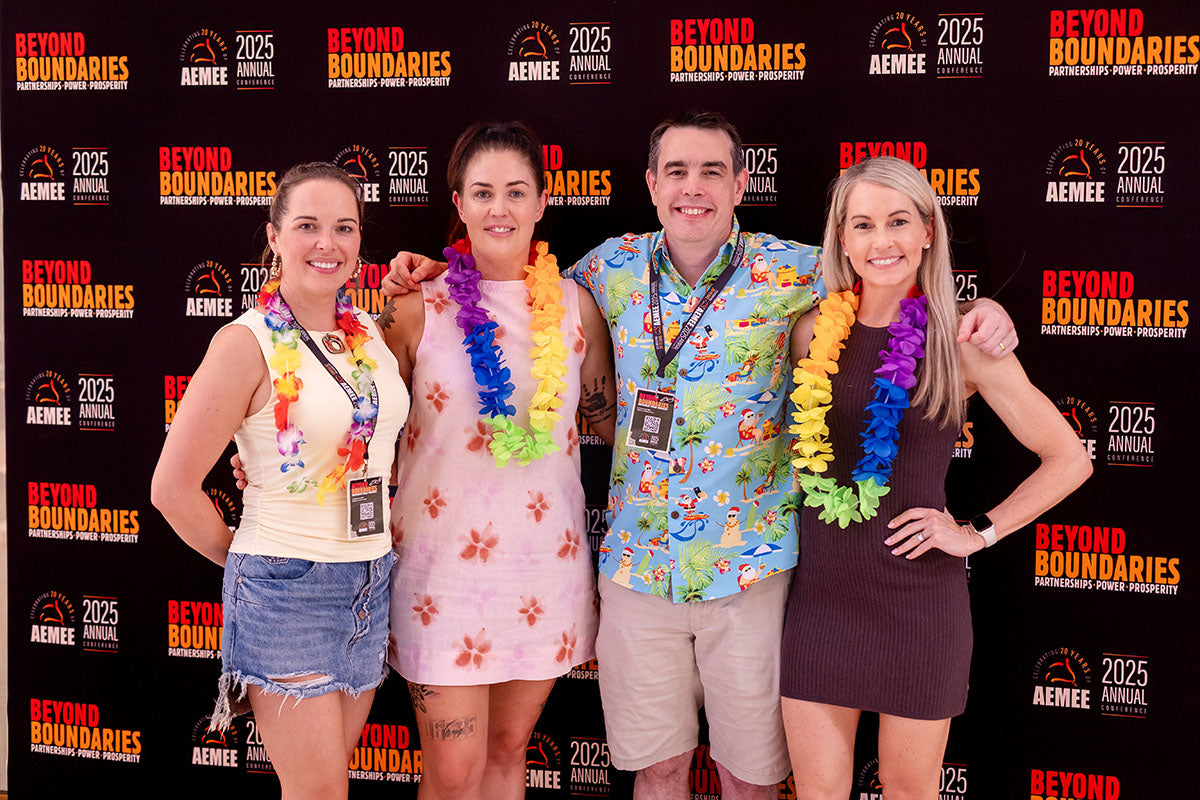 Delegates wearing Hawaiian leis at the AEMEE 2025 Annual Conference networking night — Beyond Boundaries backdrop, Darwin