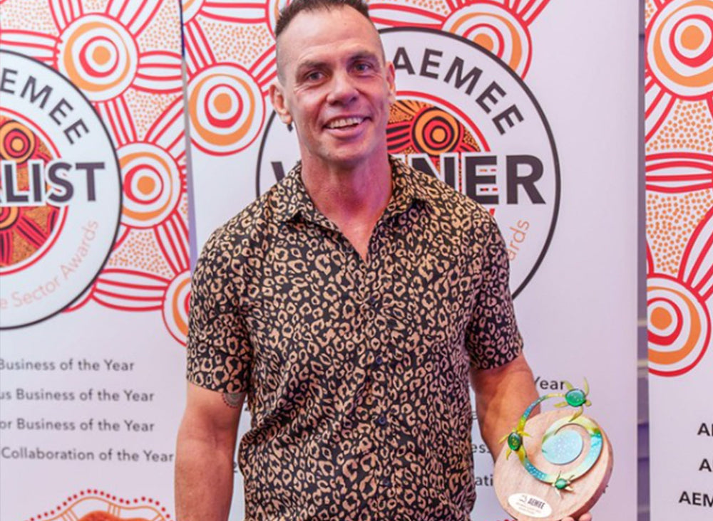 AEMEE Board Chair Derek Flucker holding a custom timber trophy at the annual conference gala dinner celebrating leadership in the Indigenous business resources sector.