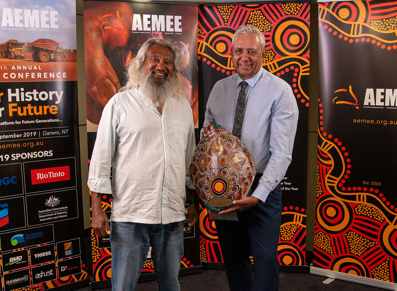 Two regional business representatives accepting a large patterned shield trophy on behalf of Djarindjin Aboriginal Corporation for the Judges Choice segment at the AEMEE conference.