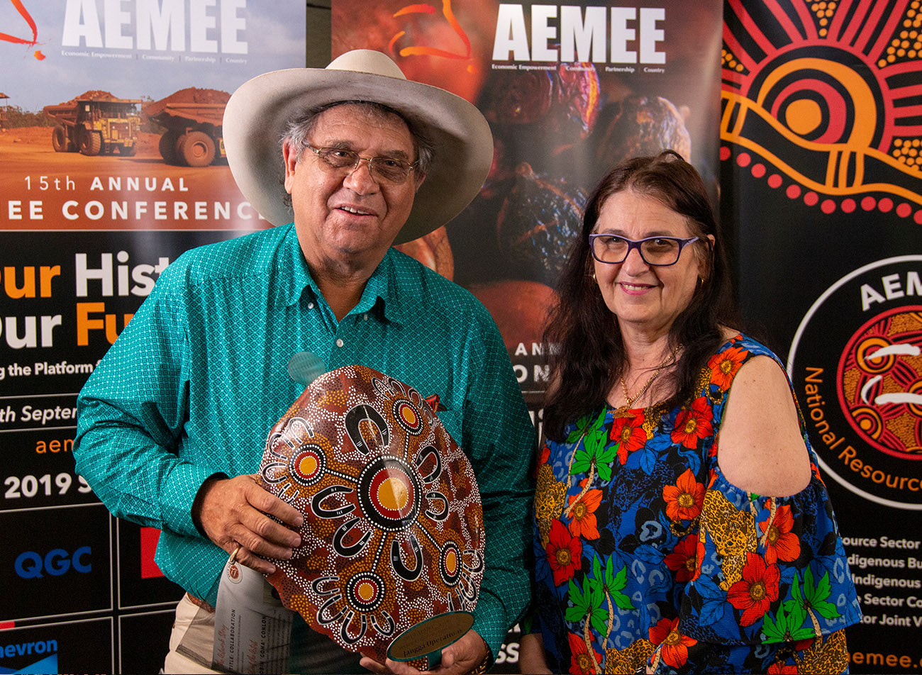 Corporate executives holding a large painted timber shield trophy representing Jangga Operations for the Resource Sector Collaboration of the Year category at the AEMEE conference.