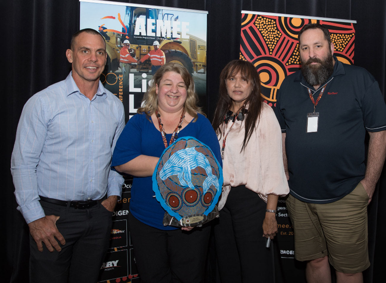 Corporate team members standing together on stage holding a blue hand-painted shield trophy for the 2018 Resource Sector Business of the Year category at an AEMEE conference.